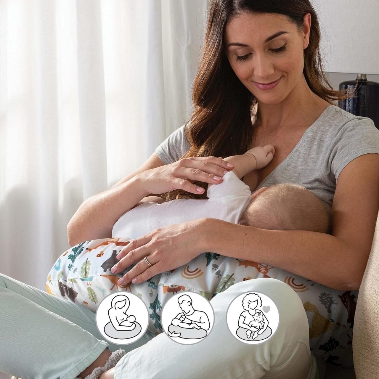 A woman breastfeeding a baby while using a printed pillow for support.