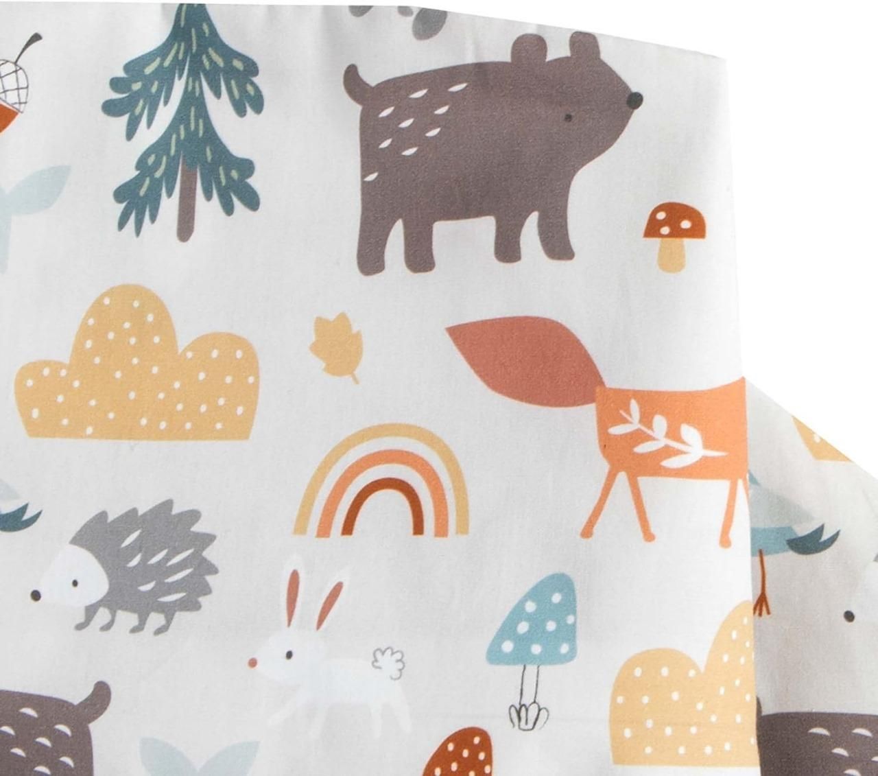 A fabric with cute, colorful illustrations of woodland animals, mushrooms, trees, a rainbow, and clouds.