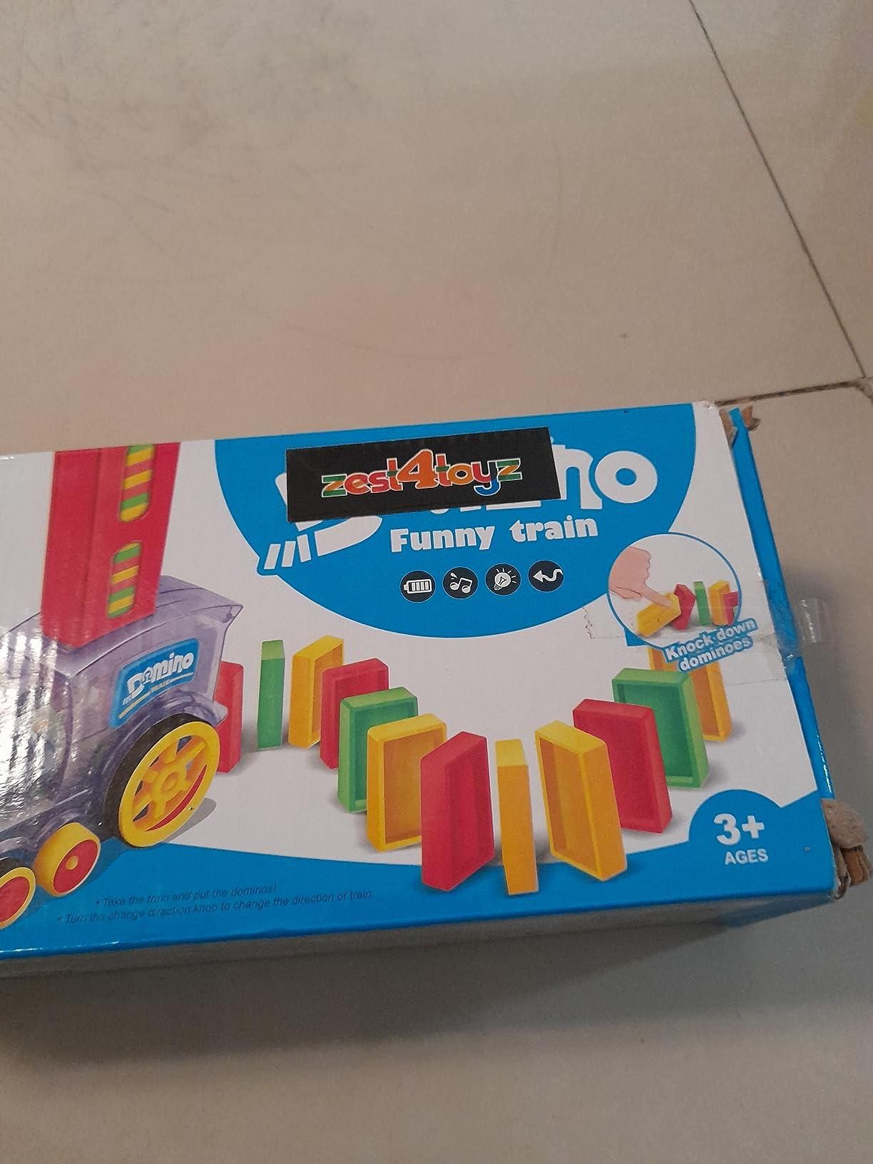 A toy box labeled 'zest4joyz Funny train' featuring a train that sets up colorful dominoes, intended for ages 3 and up.