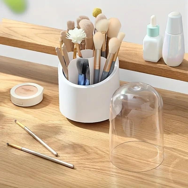 A white container holding various makeup brushes and tools on a wooden vanity, with skincare bottles, makeup powder, and two brushes nearby.