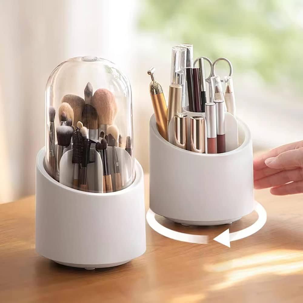 Two white rotating organizers with makeup brushes and cosmetics, one covered with a clear dome, on a wooden surface.