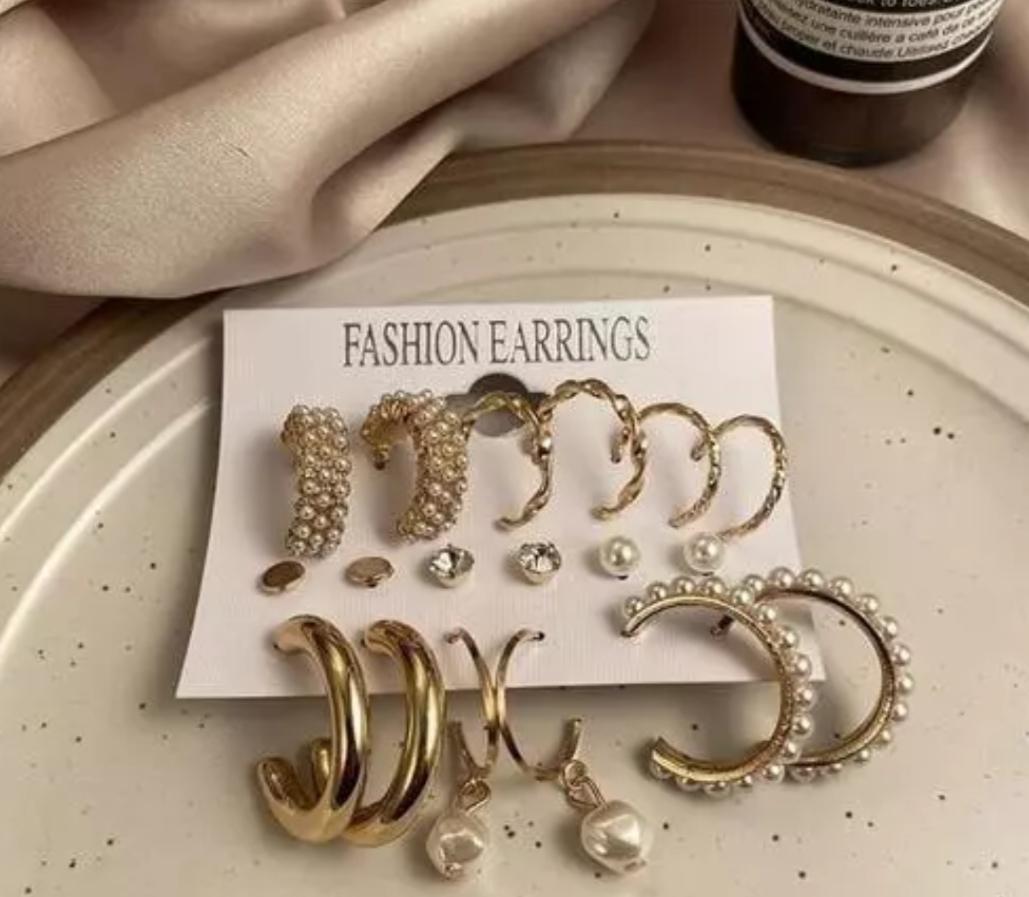A display card labeled 'Fashion Earrings' holding an assortment of gold and pearl earrings in various styles and sizes.