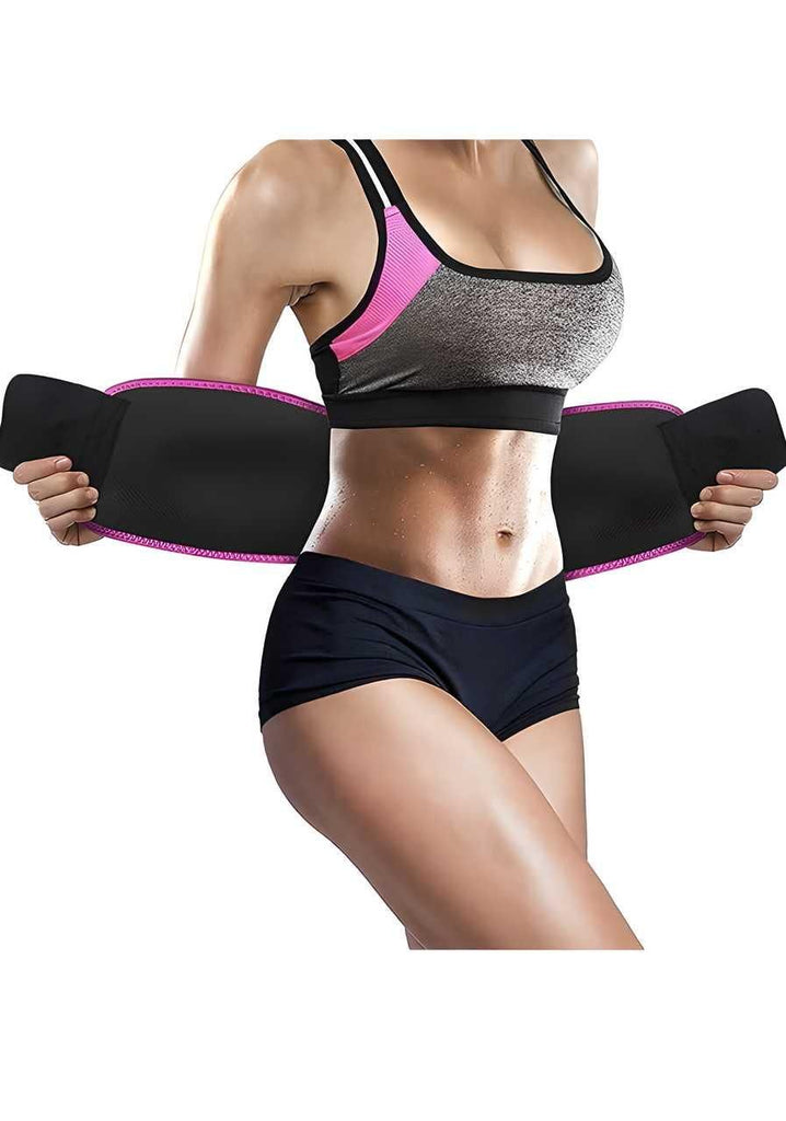 A person wearing a sports bra and shorts is opening a black and pink waist trimmer belt around their midsection.