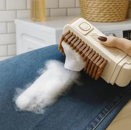A hand using a lint remover brush to collect pet hair or lint from blue jeans.