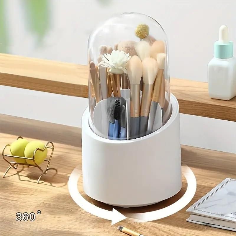 A white rotating makeup brush organizer with a clear lid, holding various brushes and tools on a wooden surface.