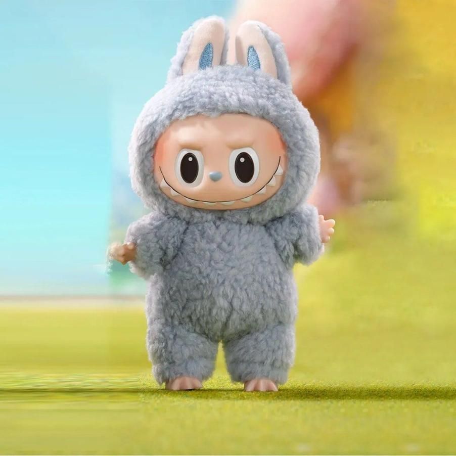 A toy figure wearing a fluffy gray bunny costume with big eyes and a wide, toothy grin, standing on grass.
