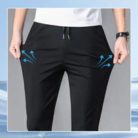 A person stretching the sides of black drawstring pants, demonstrating their elasticity with illustrated blue arrows.