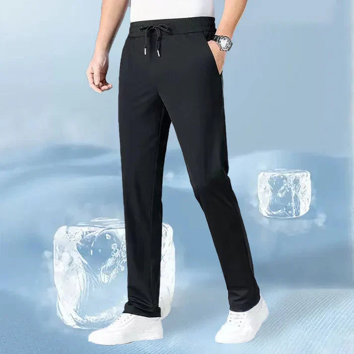A person wearing black drawstring pants and white sneakers, with ice cubes in the background.
