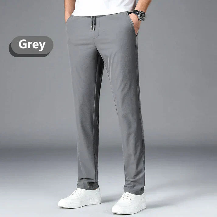 A person wearing grey casual pants with white sneakers and a white shirt.
