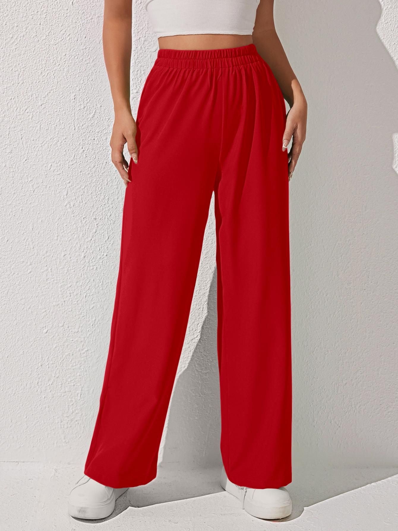 A person wearing red wide-leg pants with a white crop top and white shoes.