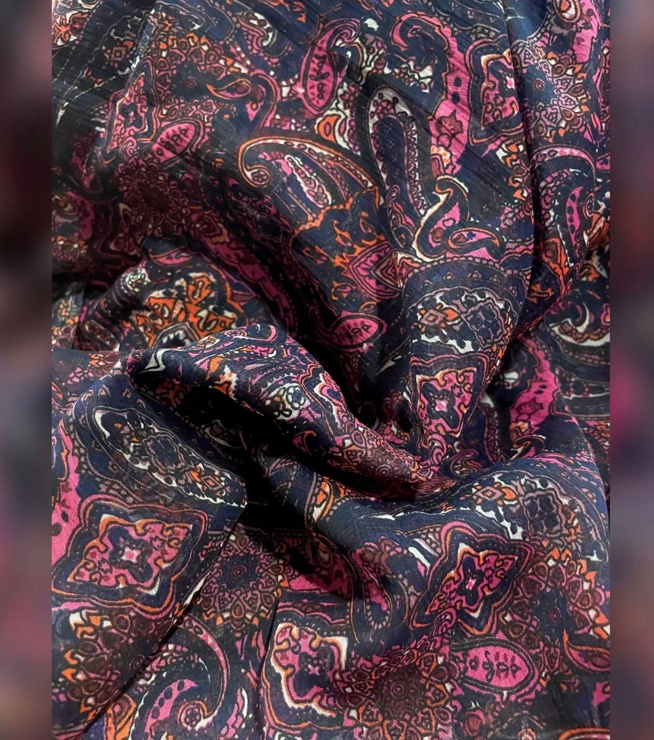 A close-up of fabric with a colorful paisley and floral pattern in shades of pink, orange, and purple.